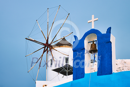 Old traditional whitewashed greek windmill and orthodox christian church bell on Santorini island in Oia town. Oia village, Santorini, Greece Old traditional whitewashed greek windmill and orthodox christian church bell on Santorini island in Oia town. Oia village, Santorini, Greece