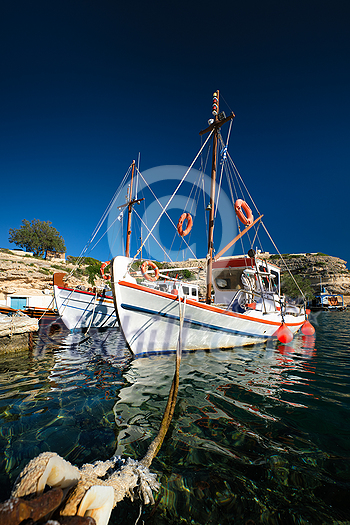 Fishing boats moored in crystal clear turquoise sea water in harbour in Greek fishing village of Mandrakia, Milos island, Greece. Horizontal camera pan Fishing boats moored in crystal clear turquoise sea water in harbour in Greek fishing village of Mandrakia, Milos island, Greece. Horizontal camera pan