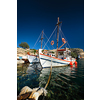 Fishing boats moored in crystal clear turquoise sea water in harbour in Greek fishing village of Mandrakia, Milos island, Greece. Horizontal camera pan