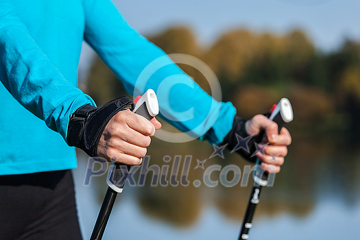 Nordic walking exercise adventure hiking concept - closeup of woman's hand holding nordic walking poles Nordic walking exercise adventure hiking concept - closeup of woman's hand holding nordic walking poles