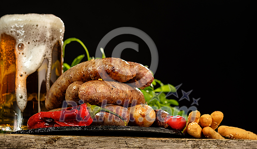 Grilled sausages with a glass of beer on a wooden table. Rustic style. Snacks for the Oktoberfest. Grilled sausages with a glass of beer on a wooden table. Rustic style. Snacks for the Oktoberfest.