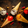 Different varieties of ice cream in waffle cones on the table, top view.