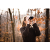 Young woman with binoculars outdoors on fall day. Enjoying the outdoors.