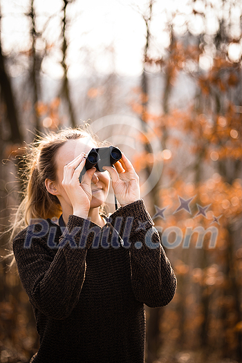 Young woman with binoculars outdoors on fall day. Enjoying the outdoors. Young woman with binoculars outdoors on fall day. Enjoying the outdoors.