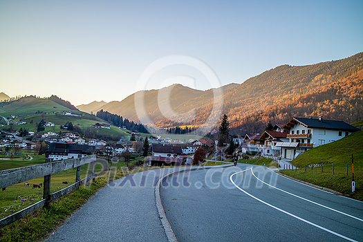 Beautiful landscape with asphalt road through the traditional country in Austria on a background of mountains and clear blue sky in a sunny day. Beautiful landscape with asphalt road through the traditional country in Austria on a background of mountains and clear blue sky in a sunny day.