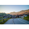 Beautiful landscape with asphalt road through the traditional country in Austria on a background of mountains and clear blue sky in a sunny day.