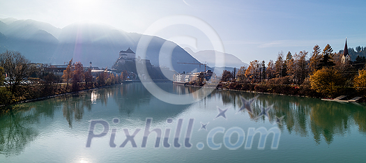 Amazing tranquil autumn landscape with smooth water surface of Inn river before beautiful view of Kufstein Fortress and boardwalk along river. Kufstein, Austria. Amazing tranquil autumn landscape with smooth water surface of Inn river before beautiful view of Kufstein Fortress and boardwalk along river. Kufstein, Austria.