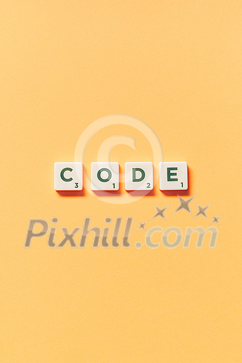 Code word formed of scrabble blocks on yellow background. Creative template with copy space. Code word formed of scrabble blocks on yellow background. Creative template with copy space.