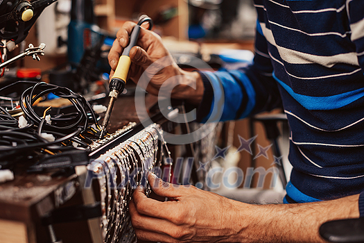 Industrial worker man soldering cables of manufacturing equipment in a factory. Selective focus. High-quality photo Industrial worker man soldering cables of manufacturing equipment in a factory. Selective focus. High-quality photo