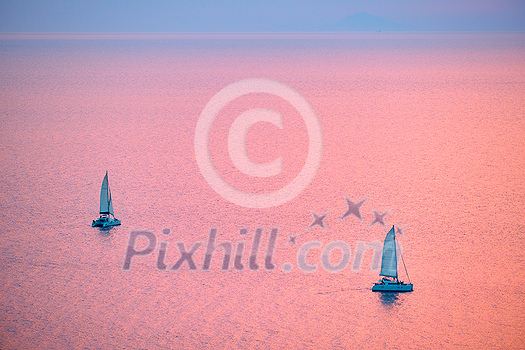 Tourist yachts boat in Aegean sea near Santorini island with tourists watching sunset from viewpoint. Santorini, Greece Tourist yachts boat in Aegean sea near Santorini island with tourists watching sunset from viewpoint. Santorini, Greece