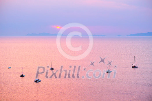 Tourist yachts boat in Aegean sea near Santorini island with tourists watching sunset from viewpoint. Santorini, Greece Tourist yachts boat in Aegean sea near Santorini island with tourists watching sunset from viewpoint. Santorini, Greece