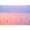 Tourist yachts boat in Aegean sea near Santorini island with tourists watching sunset from viewpoint. Santorini, Greece