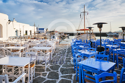 Cafe tables on quay of Naousa town port in famous tourist attraction Paros island, Greece on sunrise
