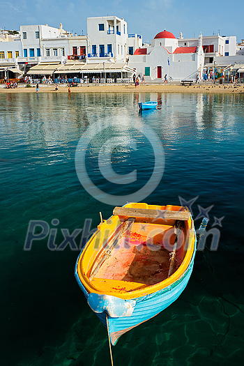 Blue fishing boat in port harbor of Chora town on Mykonos island with orthodox church in background, Greece Blue fishing boat in port harbor of Chora town on Mykonos island with orthodox church in background, Greece