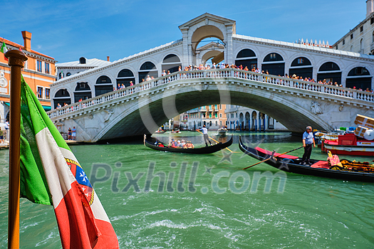 Italian maritime flag with Rialto bridge with boats and gondolas in the bacground. Grand Canal, Venice, Italy Italian maritime flag with Rialto bridge with boats and gondolas in the bacground. Grand Canal, Venice, Italy
