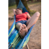 Young woman resting on hammock while enjoying nature on the river bank