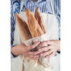 Close-up image of woman holding package of fresh baguettes