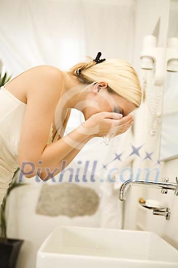 Woman washing her face in the bathroom Woman washing her face in the bathroom