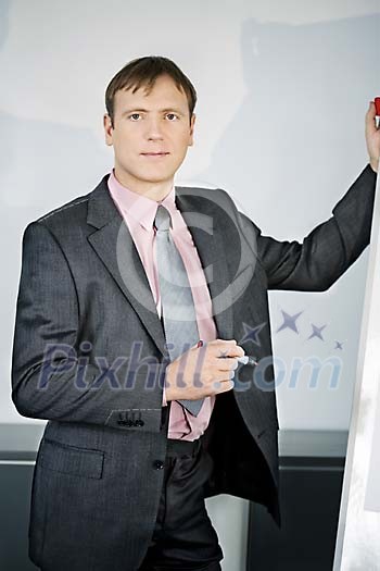 Businessman holding a pen next to the board Businessman holding a pen next to the board