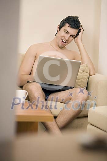 Man sitting on the couch looking at his laptop Man sitting on the couch looking at his laptop