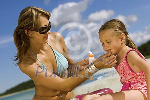 Woman putting suncream on her daughter Woman putting suncream on her daughter