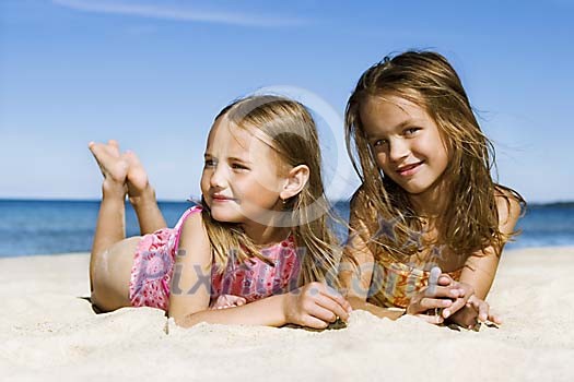 Two girls lying on the sand