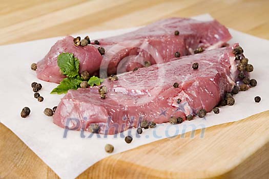 Raw meat stake with pepper on a paper Raw meat stake with pepper on a paper