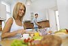 Woman and man in the kitchen prepearing and having breakfast