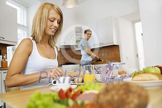 Woman and man prepearing and having breakfast Woman and man prepearing and having breakfast