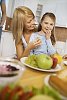 Woman and girl having grapes on the kitchen table