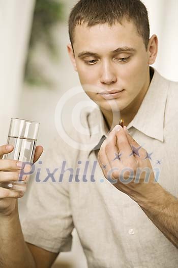 Man holding a pill and a glass of water Man holding a pill and a glass of water