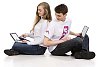 Couple of teenagers sitting on the floor with laptops