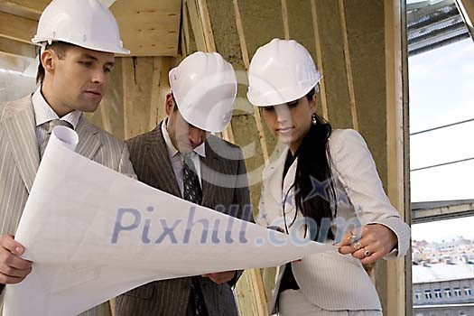 Men and a woman checking construction plans Men and a woman checking construction plans