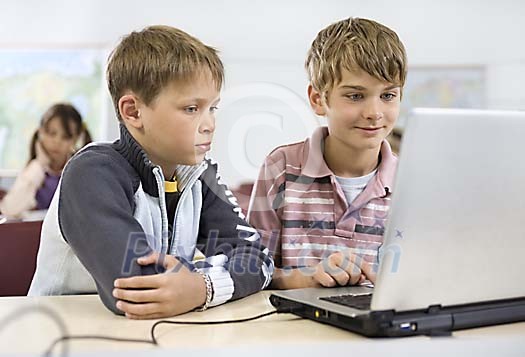 Two schoolboys with a laptop in the classroom Two schoolboys with a laptop in the classroom