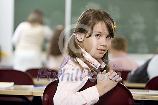 Schoolgirl looking behind in the classroom Schoolgirl looking behind in the classroom