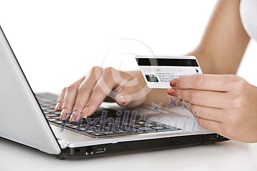 Female hands holding a credit card and touching a laptop Female hands holding a credit card and touching a laptop