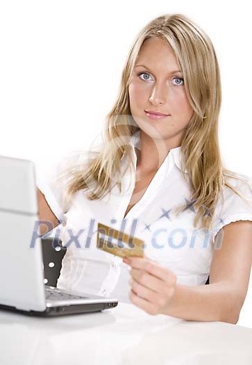 Woman sitting behind a laptop with a credit card in her hand Woman sitting behind a laptop with a credit card in her hand