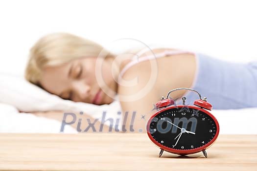 Blurred woman sleeping with alarm clock on display