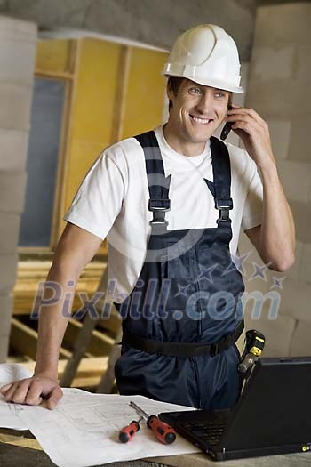 Male carpenter on the phone at worksite Male carpenter on the phone at worksite