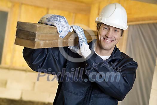 Male carpenter carrying wood at worksite