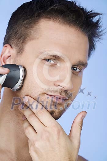 Man shaving his beard with a shaver Man shaving his beard with a shaver