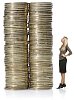 Isolated woman looking at the oversized towers of coins