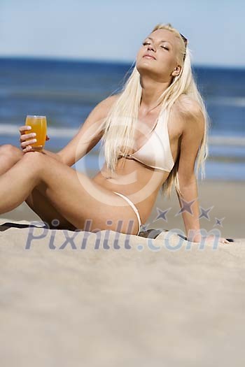 Woman in bikinis sitting on the sand, enjoying sun Woman in bikinis sitting on the sand, enjoying sun