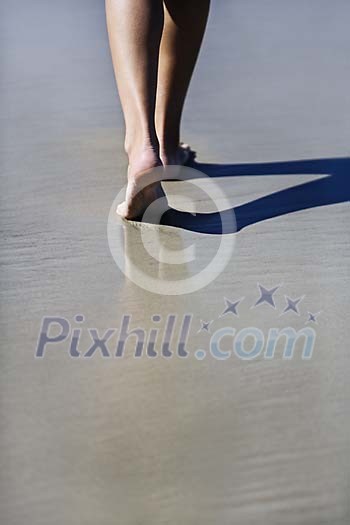 Female feet on the wet beach sand Female feet on the wet beach sand