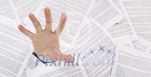 Businessmans hand reaching out from a pile of papers Businessmans hand reaching out from a pile of papers