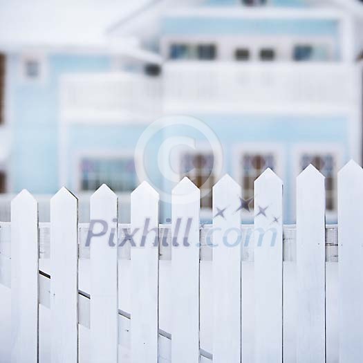 Out of focus house behind a white picket fence Out of focus house behind a white picket fence