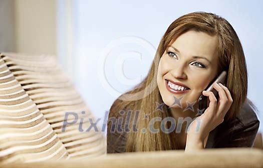 Woman on the couch talking to a phone Woman on the couch talking to a phone