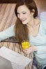 Woman sitting on the floor next to the couch with laptop and a glass of juice