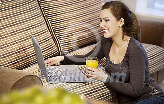 Woman sitting by the couch with laptop Woman sitting by the couch with laptop
