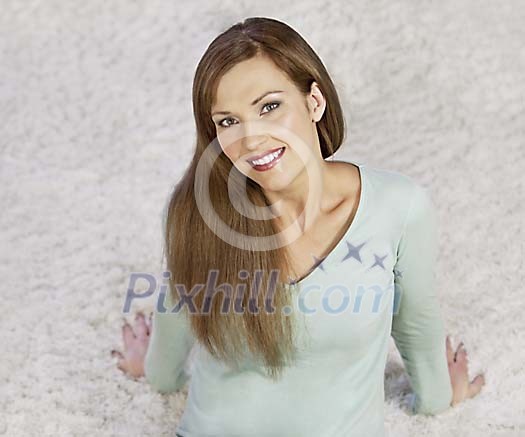 Woman sitting on the carpet smiling to camera Woman sitting on the carpet smiling to camera